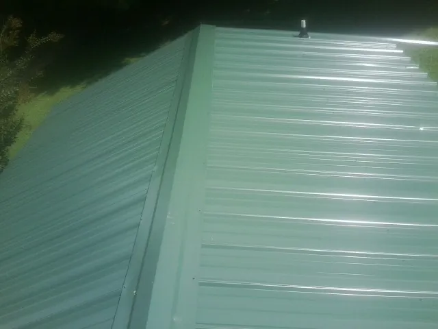 New green metal panels meeting at the ridge of a roof — Flat Roof Repair work by our crew in Big Rock
